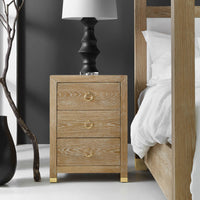 Bedside chest next to bed with lamp on top.