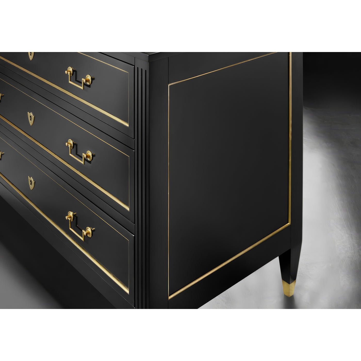 Side view of black Louis XVI dresser, gold accents.