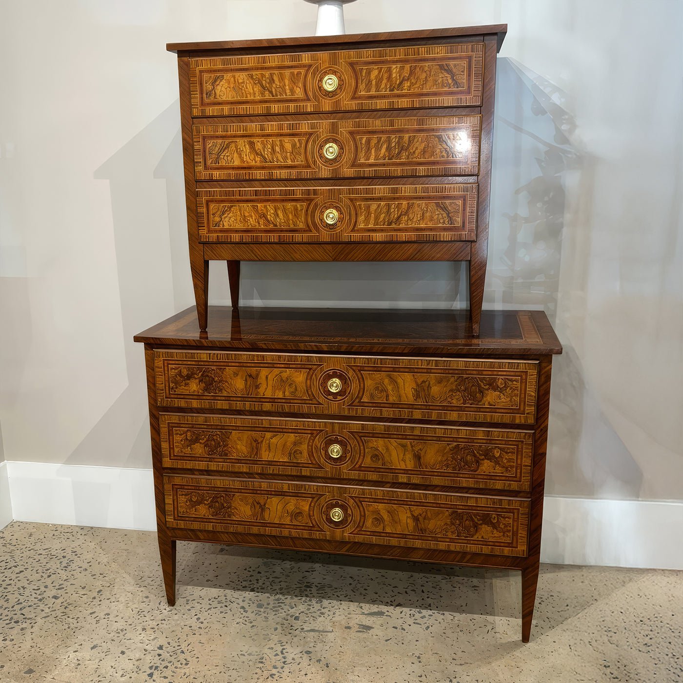 Two stacked Louis XVI style burl nightstands, showroom view.