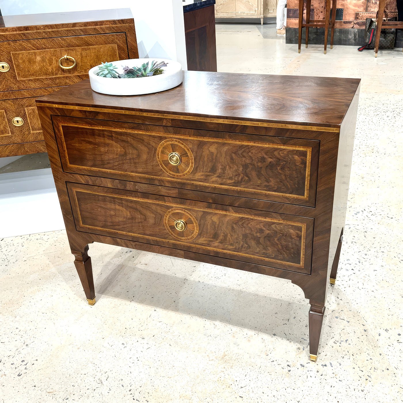 Bedside chest showcased on showroom floor with decorative plate.
