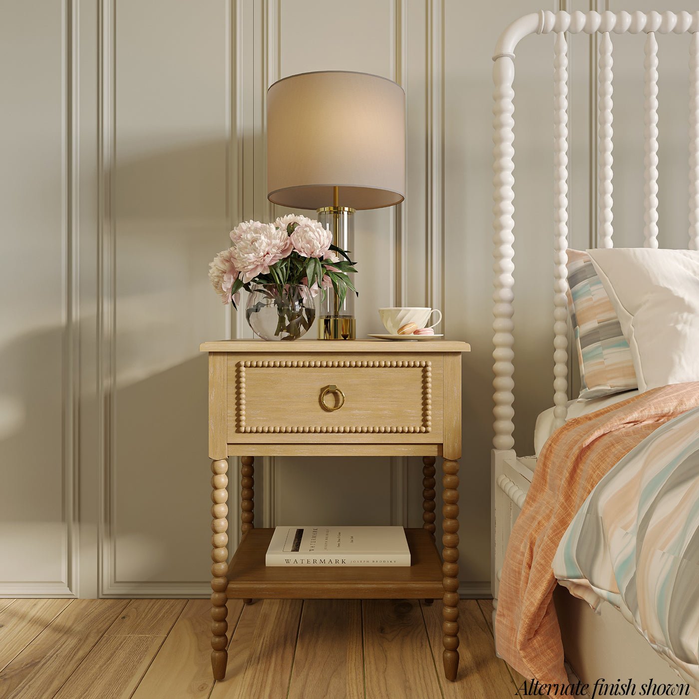 Close-up of nightstand styled with lamp and flowers.
