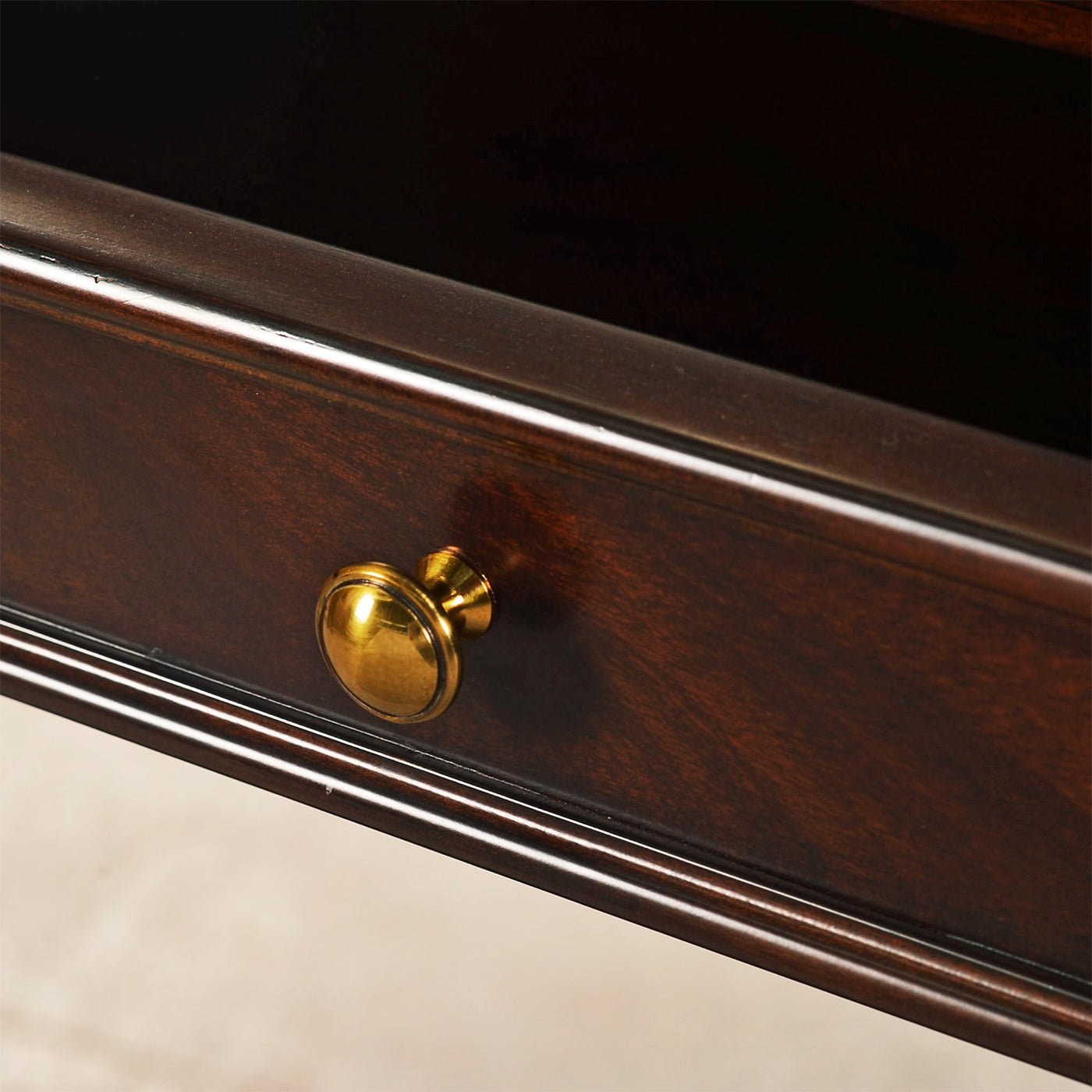 Close-up of drawer knob on mahogany console table.