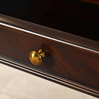 Close-up of drawer knob on mahogany console table.