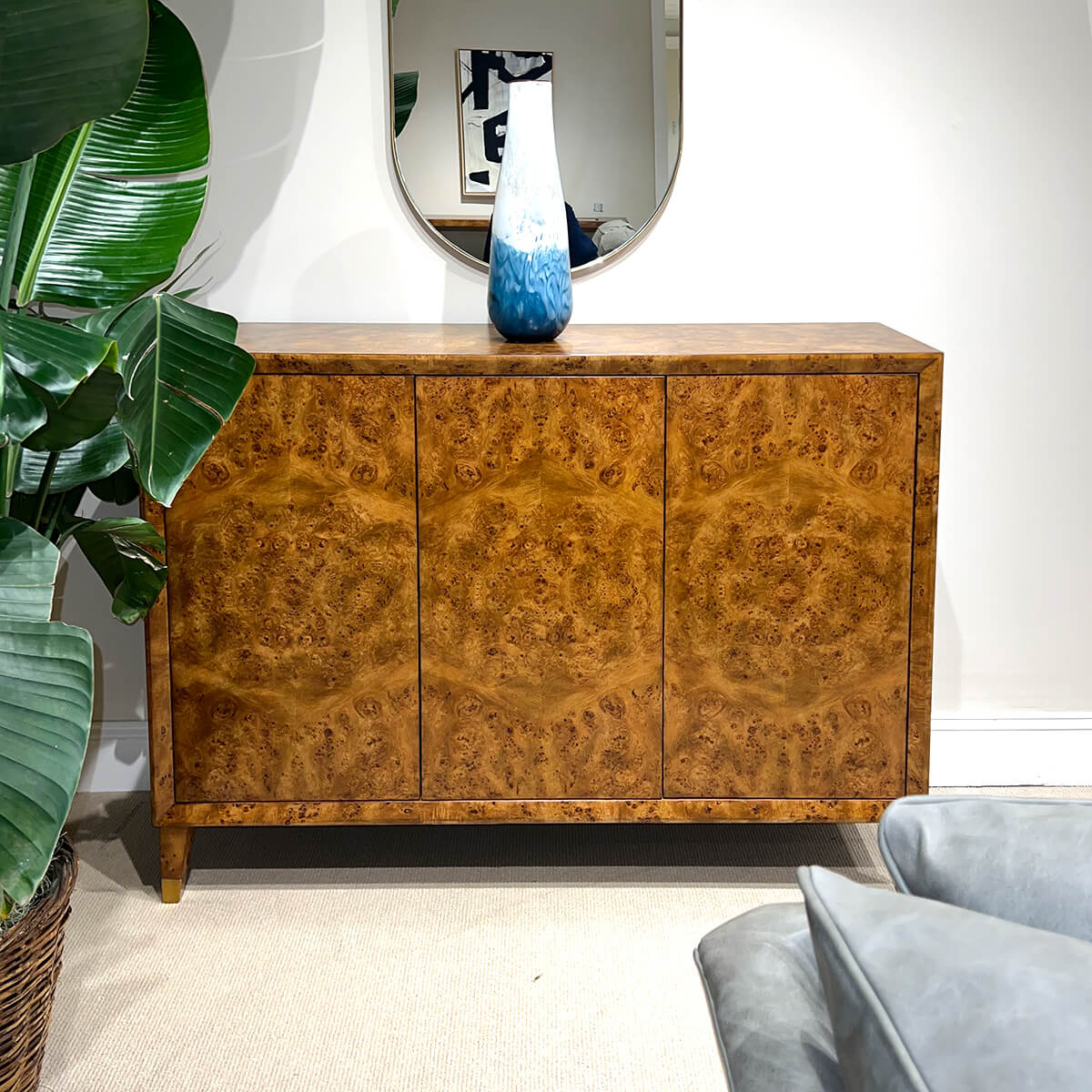 Styled mid-century burl credenza with blue vase on top.