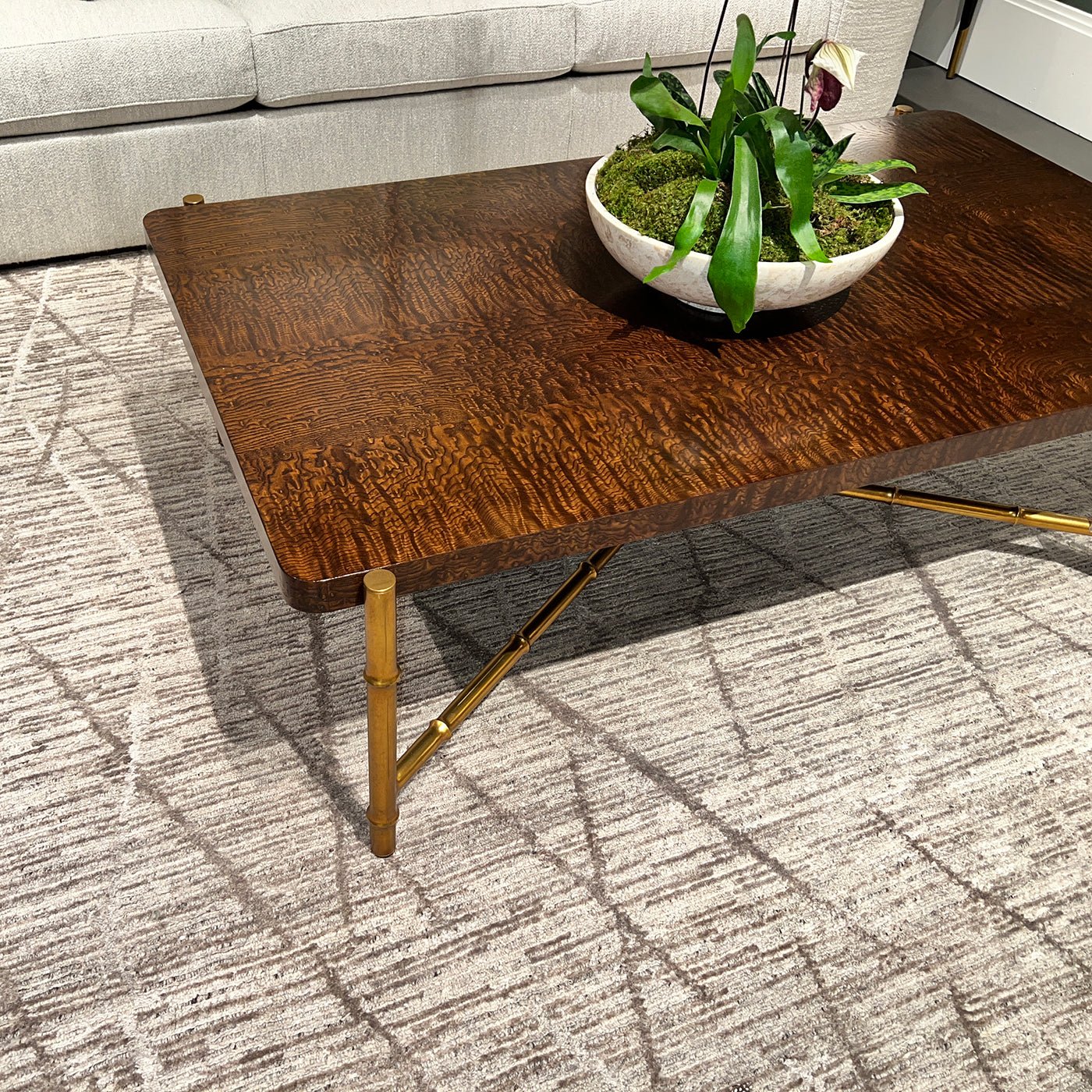 Coffee table with burl top, plant centerpiece on rug.