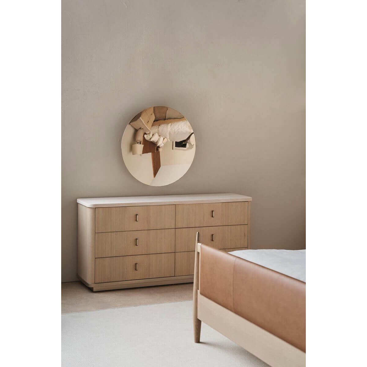 Wooden dresser with mirror beside mid-century leather queen bed.