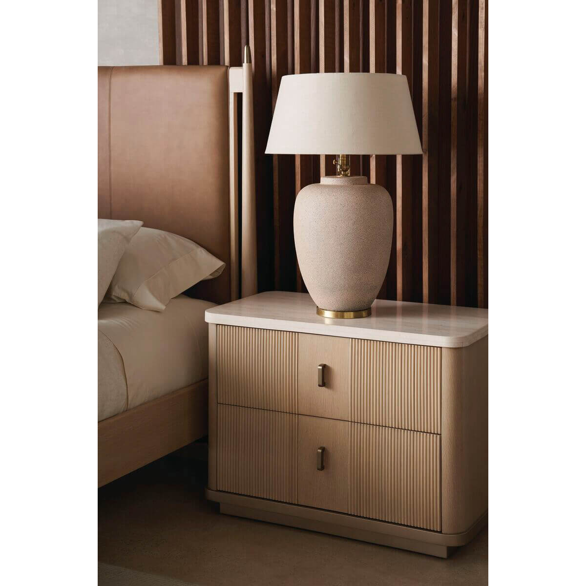 Nightstand with lamp beside mid-century leather queen bed.