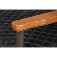 Close-up of wooden armrest on black leather chair.