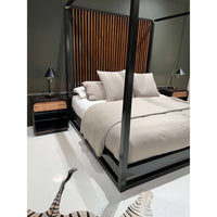 Canopy bed corner showing bedding and nightstand.
