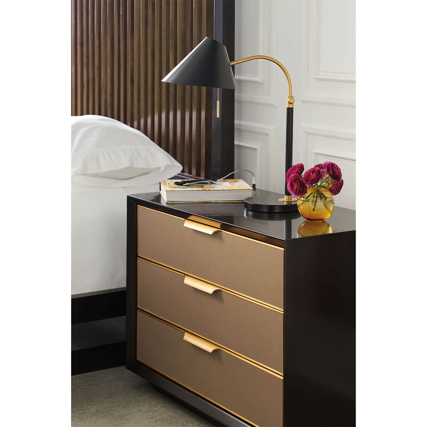 Nightstand beside modern canopy bed, lamp and decor.