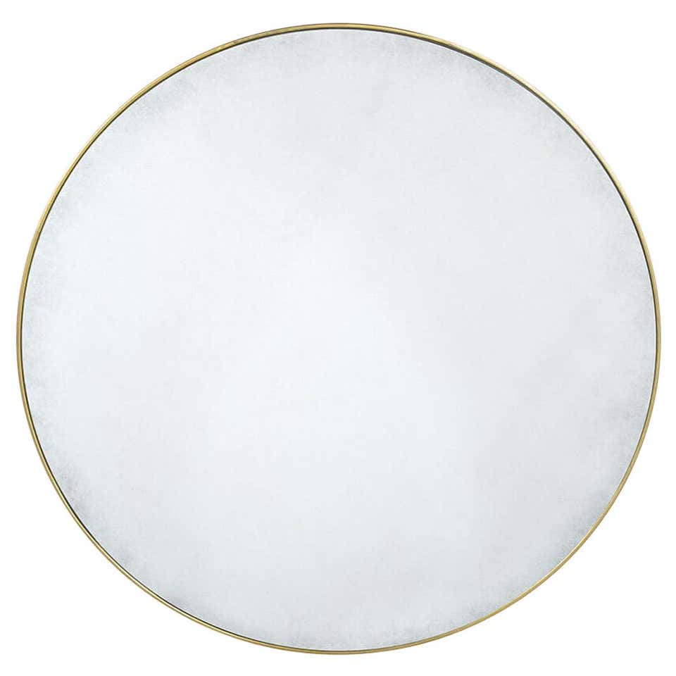Circular gilt mirror close-up on white background.