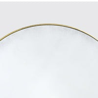 Edge of circular mirror with gilt frame detail.