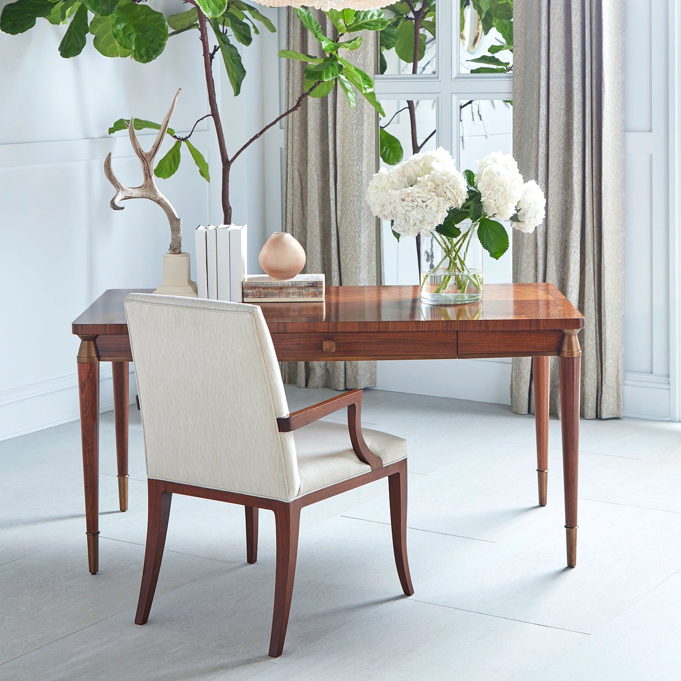 Walnut desk in a bright room setting with chair.