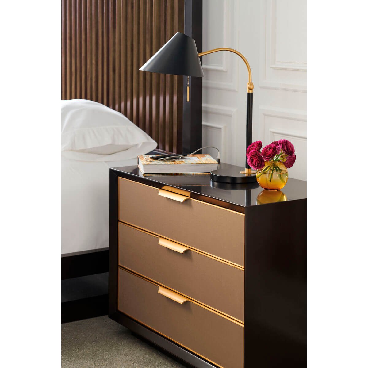 Styled mid-century modern three-drawer nightstand beside a bed