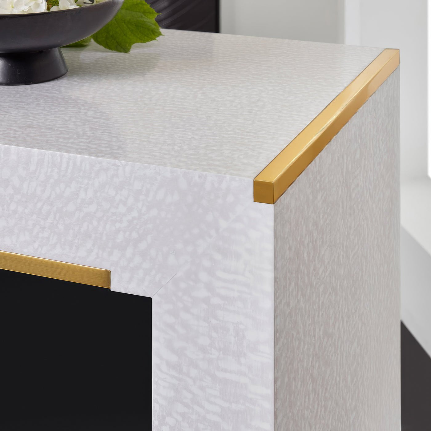 Close-up of white console table corner, gold trim detail.