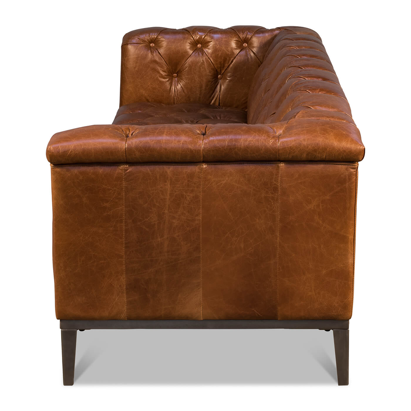 Side view of brown leather tufted sofa, wooden legs.