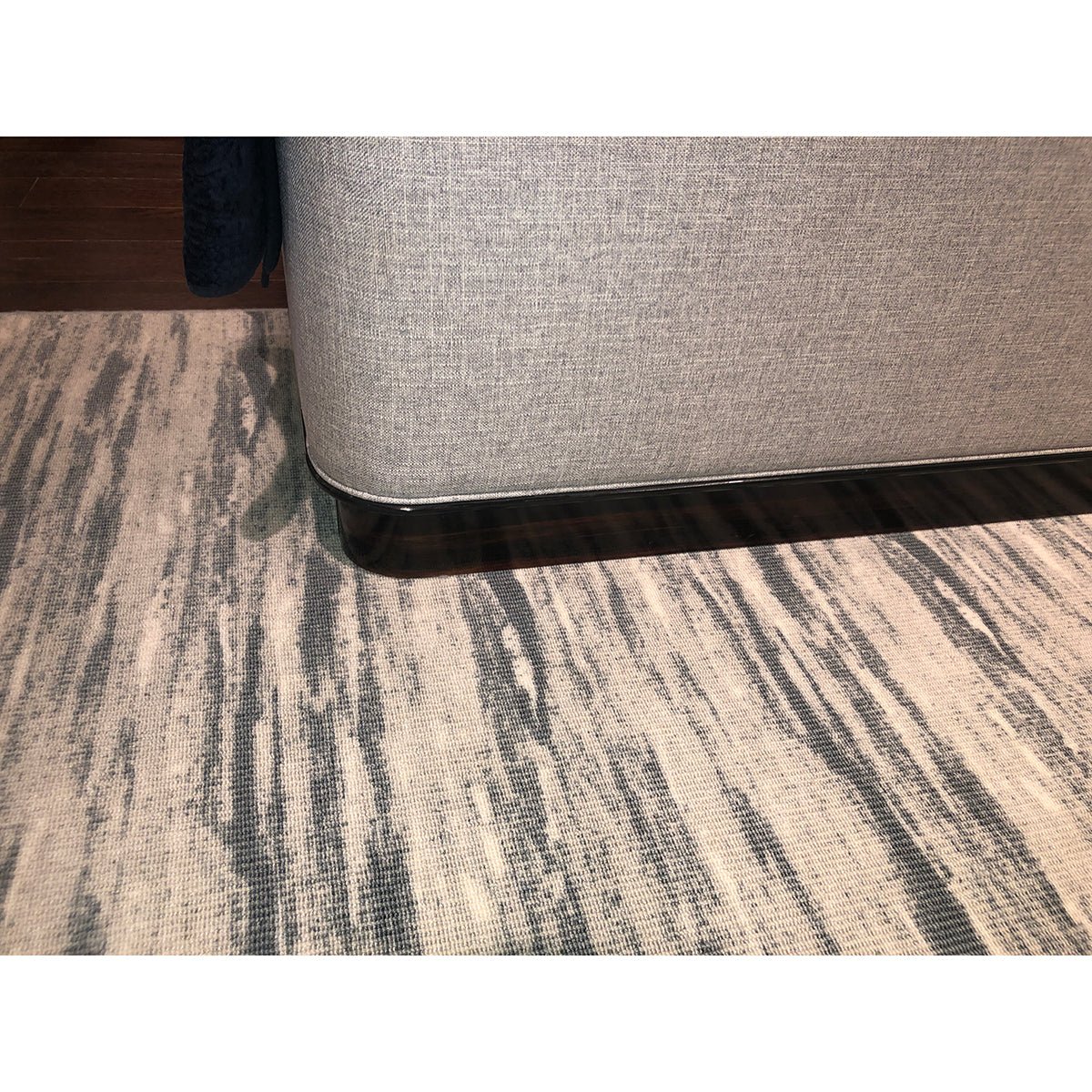 Bed corner and dark wood base on patterned rug.