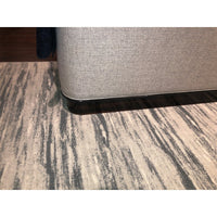 Bed corner and dark wood base on patterned rug.