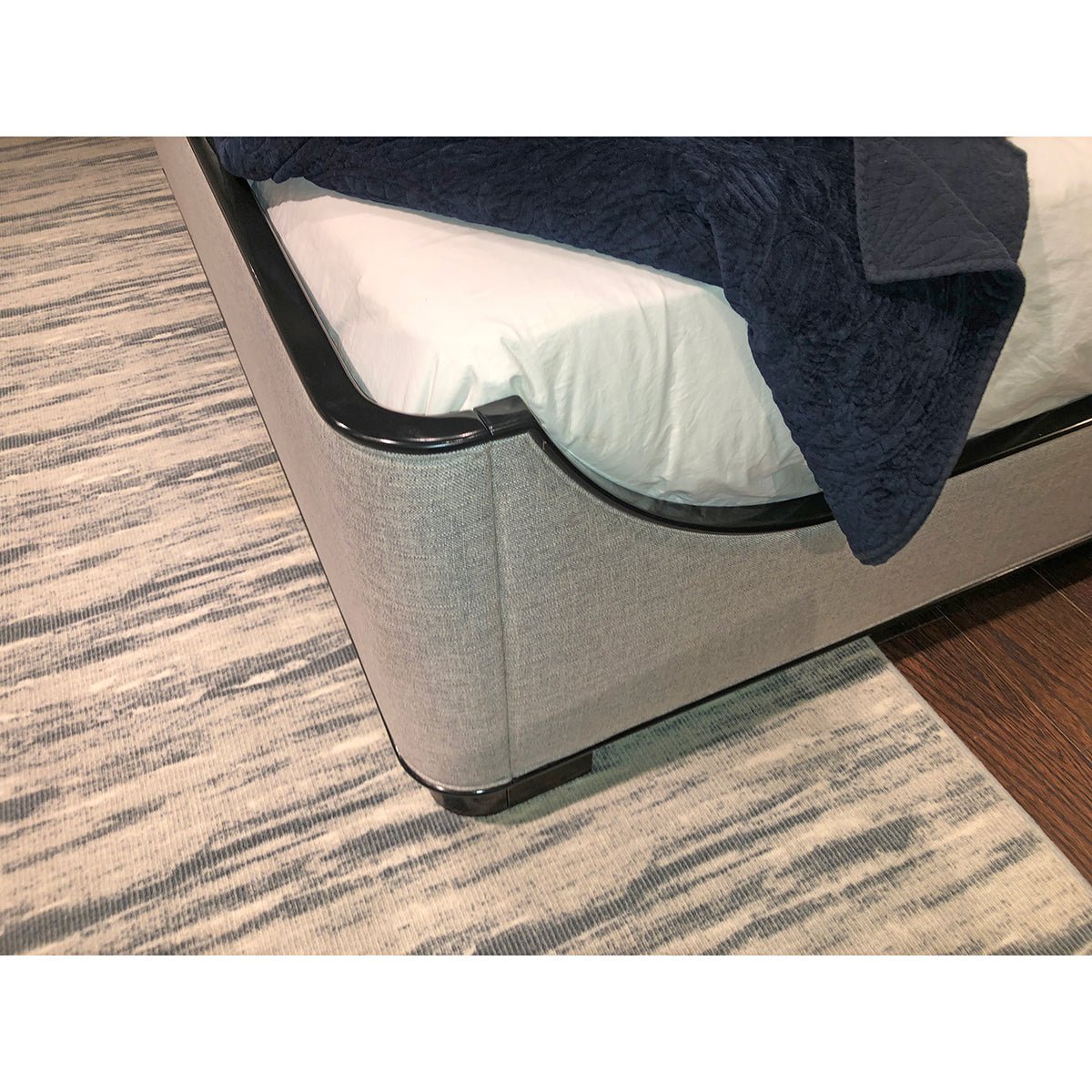 Bedding and black-trimmed corner on beige king bed.
