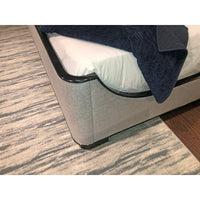 Bedding and black-trimmed corner on beige king bed.