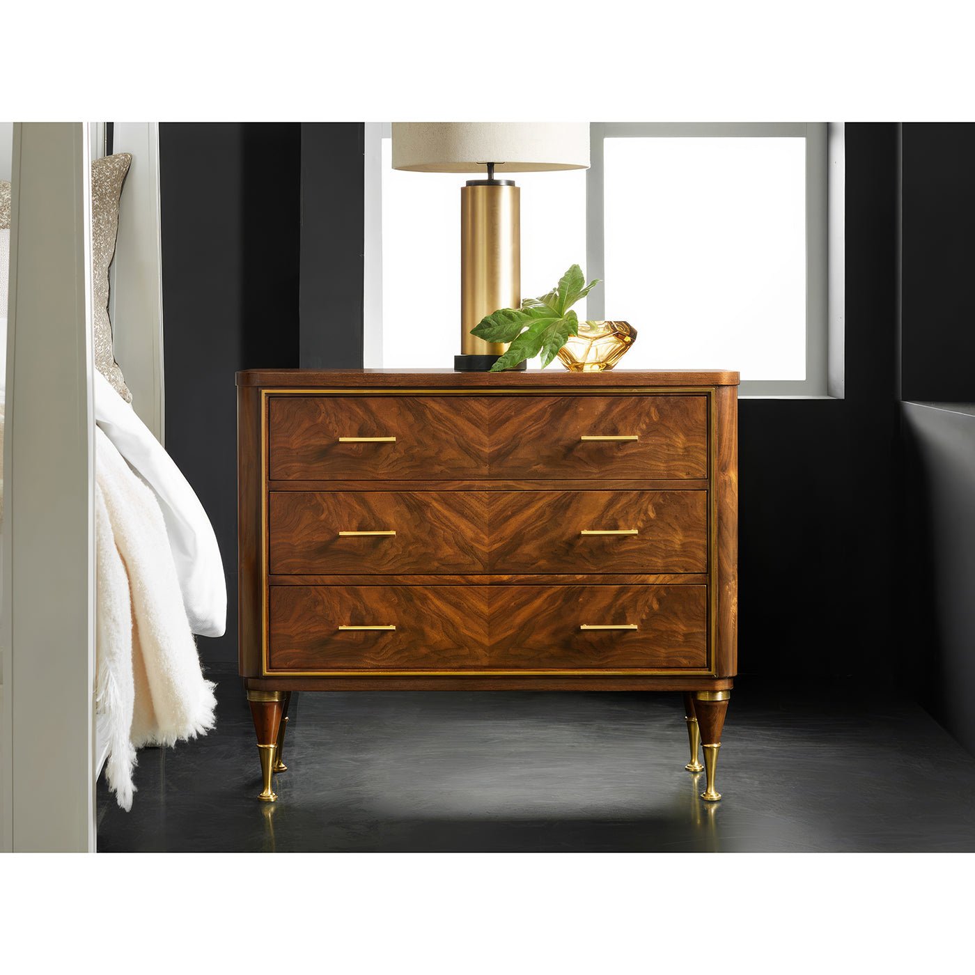 Walnut bedside chest next to bed, home setting.