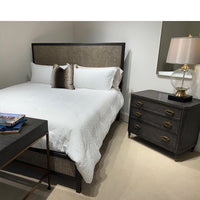 Modern bed with gray headboard, white bedding, nearby nightstand.