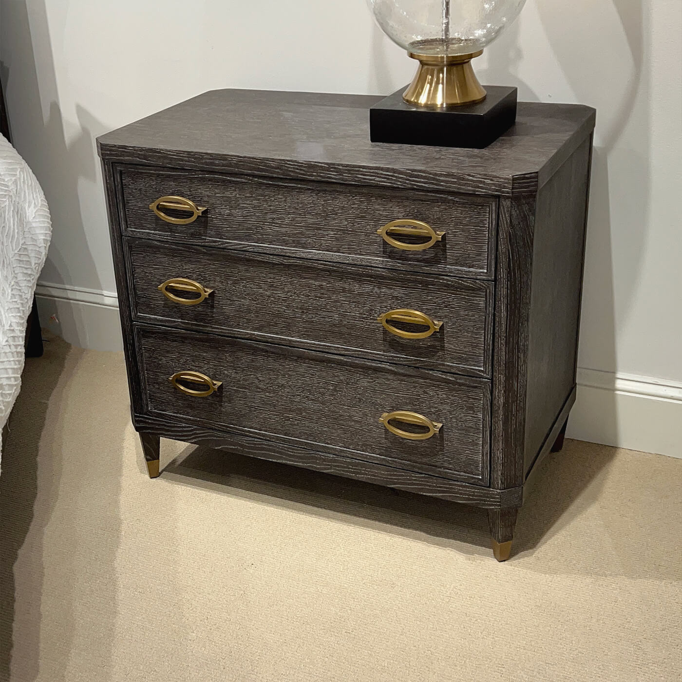 Close-up of nightstand with gold-accented lamp and decor.