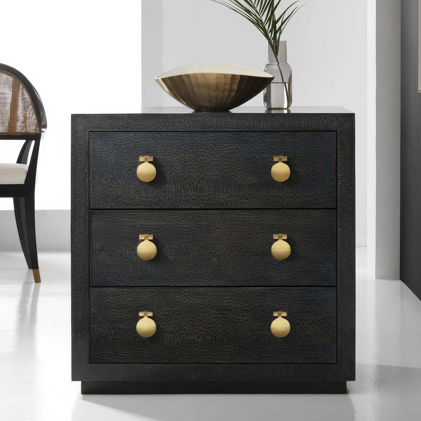 Modern black bedside chest, gold knobs, room setting.