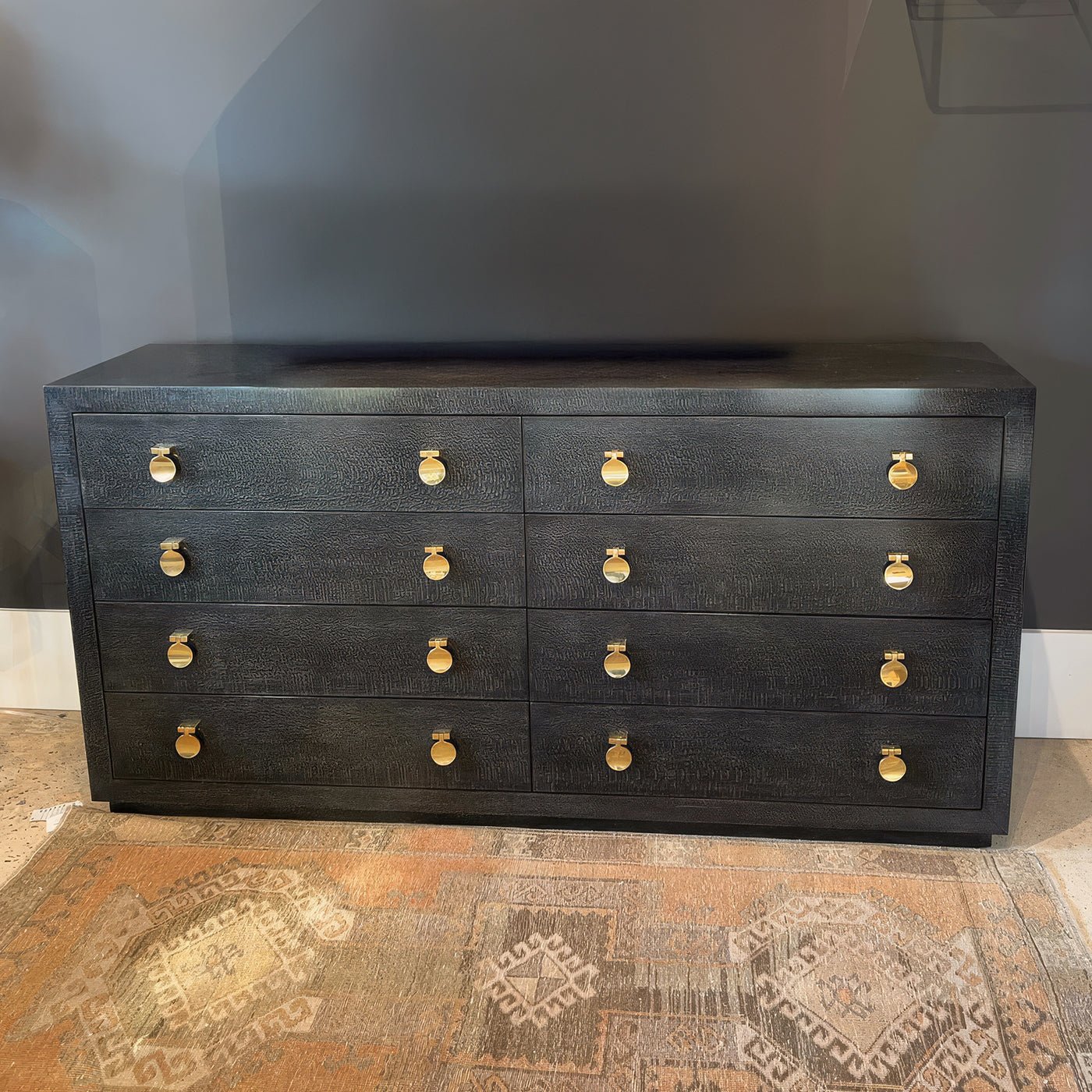 Modern black eight-drawer dresser on patterned rug background.