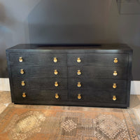 Modern black eight-drawer dresser on patterned rug background.
