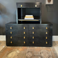 Modern black nightstand on dresser with books.