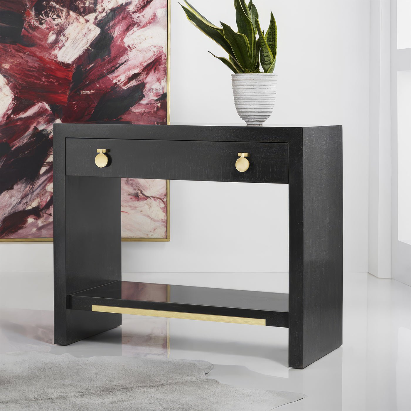 Black nightstand in styled room with plant on top.