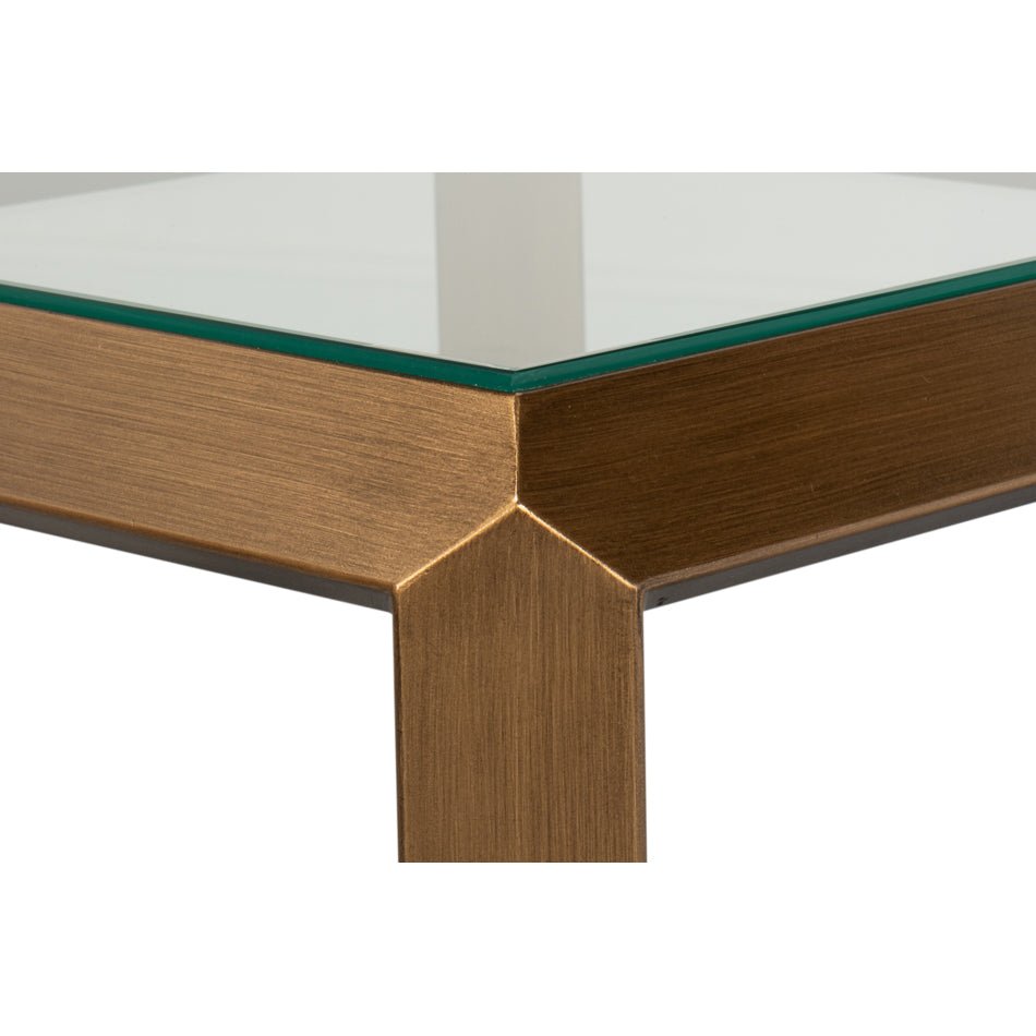 Close-up corner view of glass-top brass accent table.