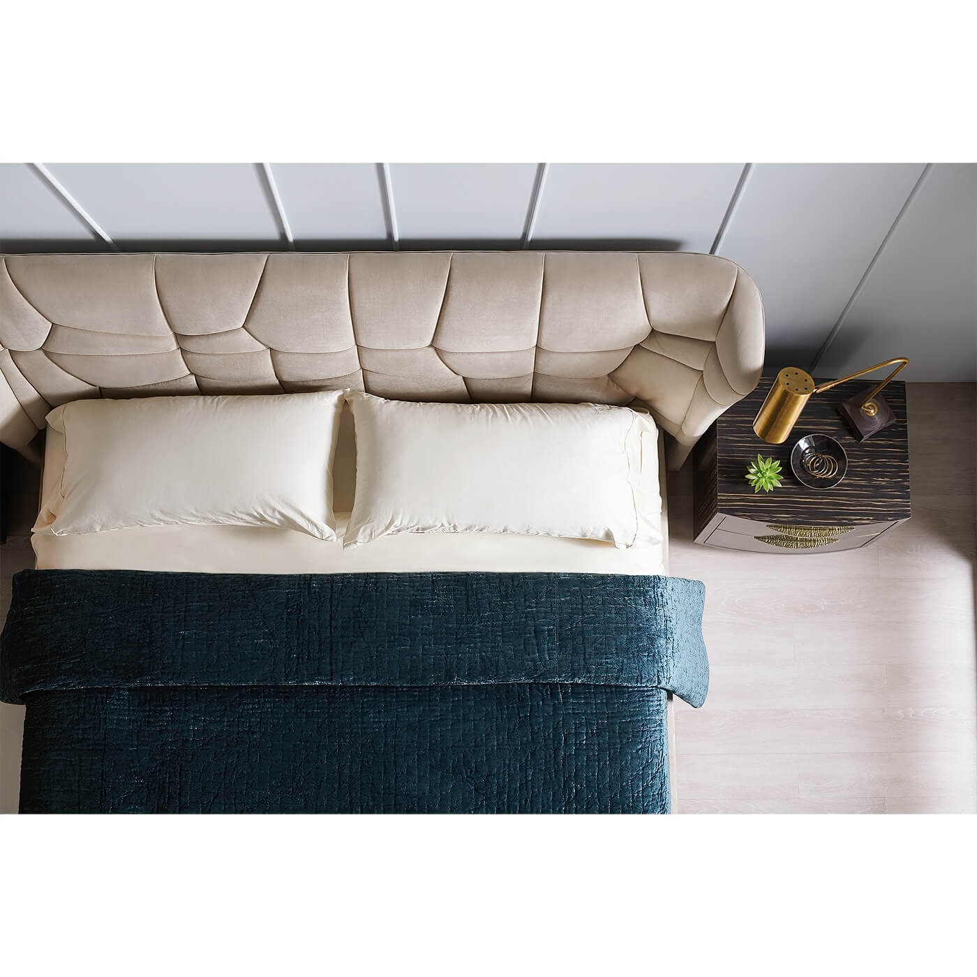 Top view of upholstered bed with pillows and side table.