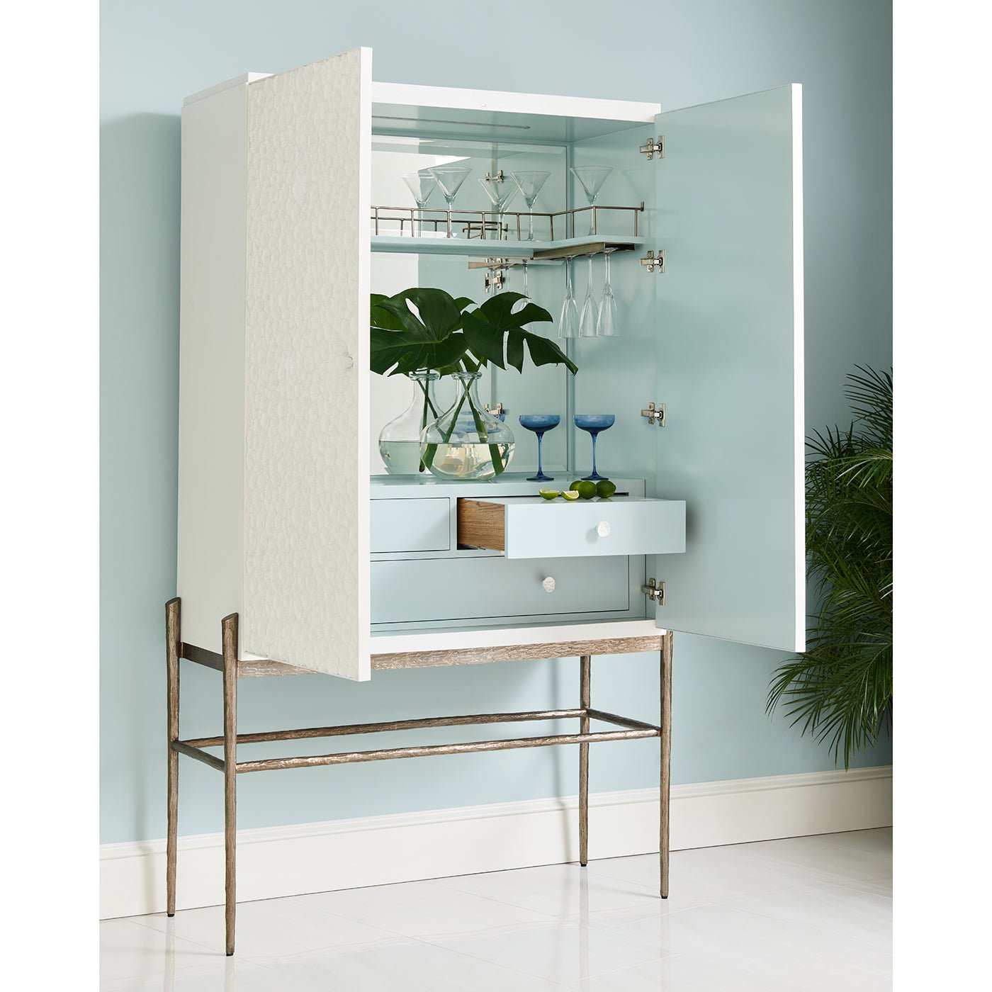 Open bar cabinet with glasses and decor inside.