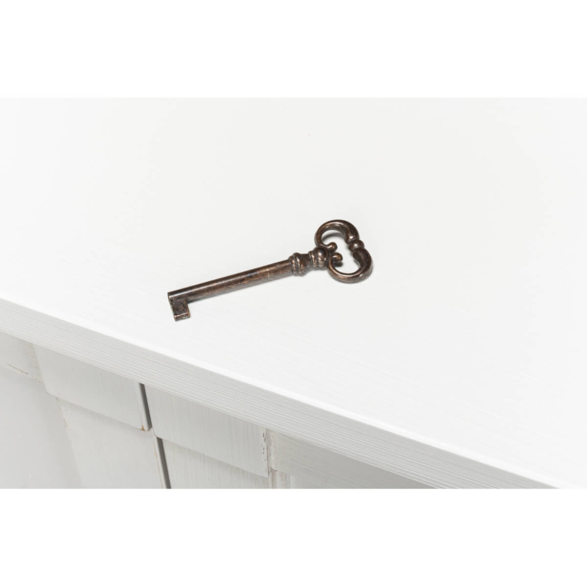 Antique-style key on white painted sideboard surface.