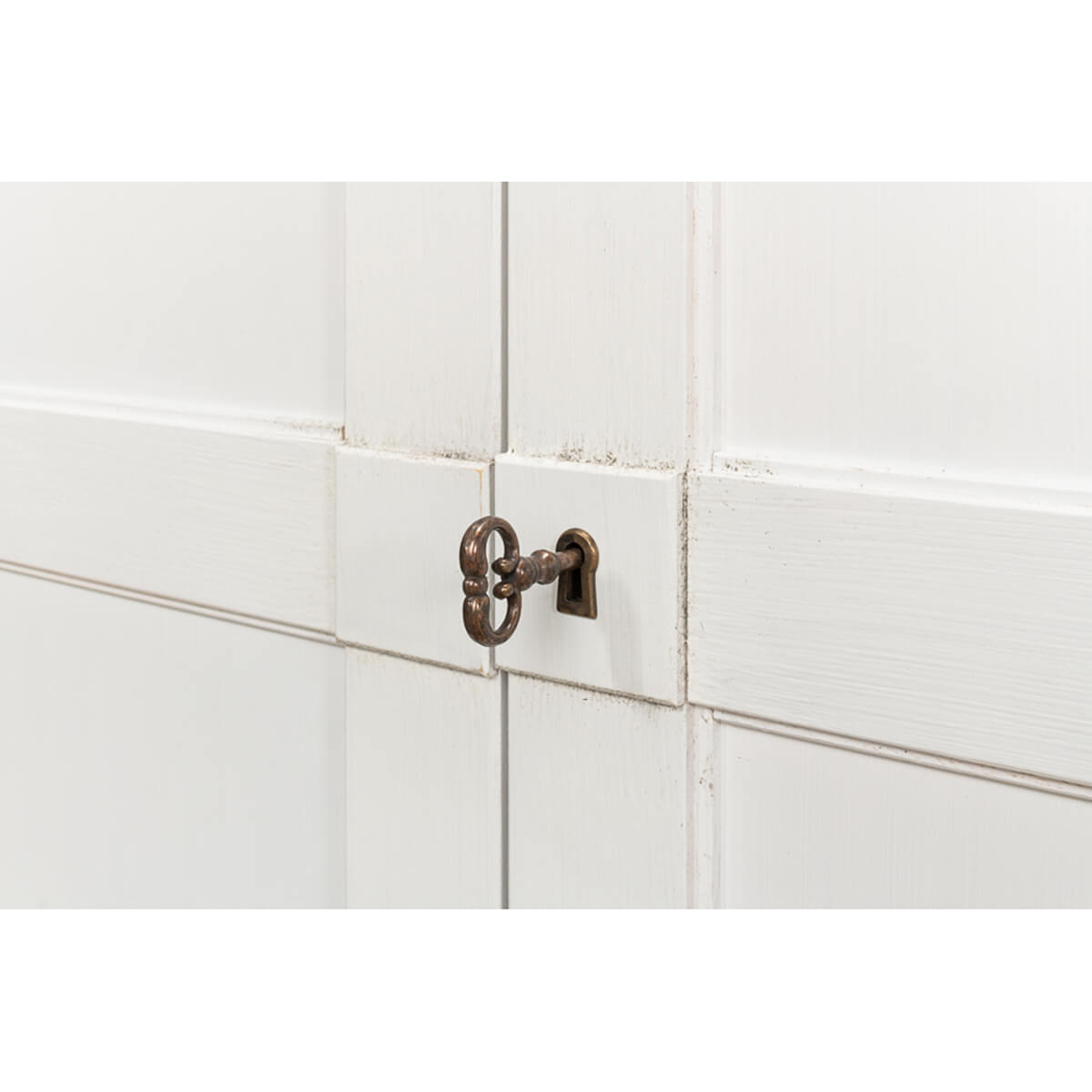Close-up of keyhole on white sideboard.