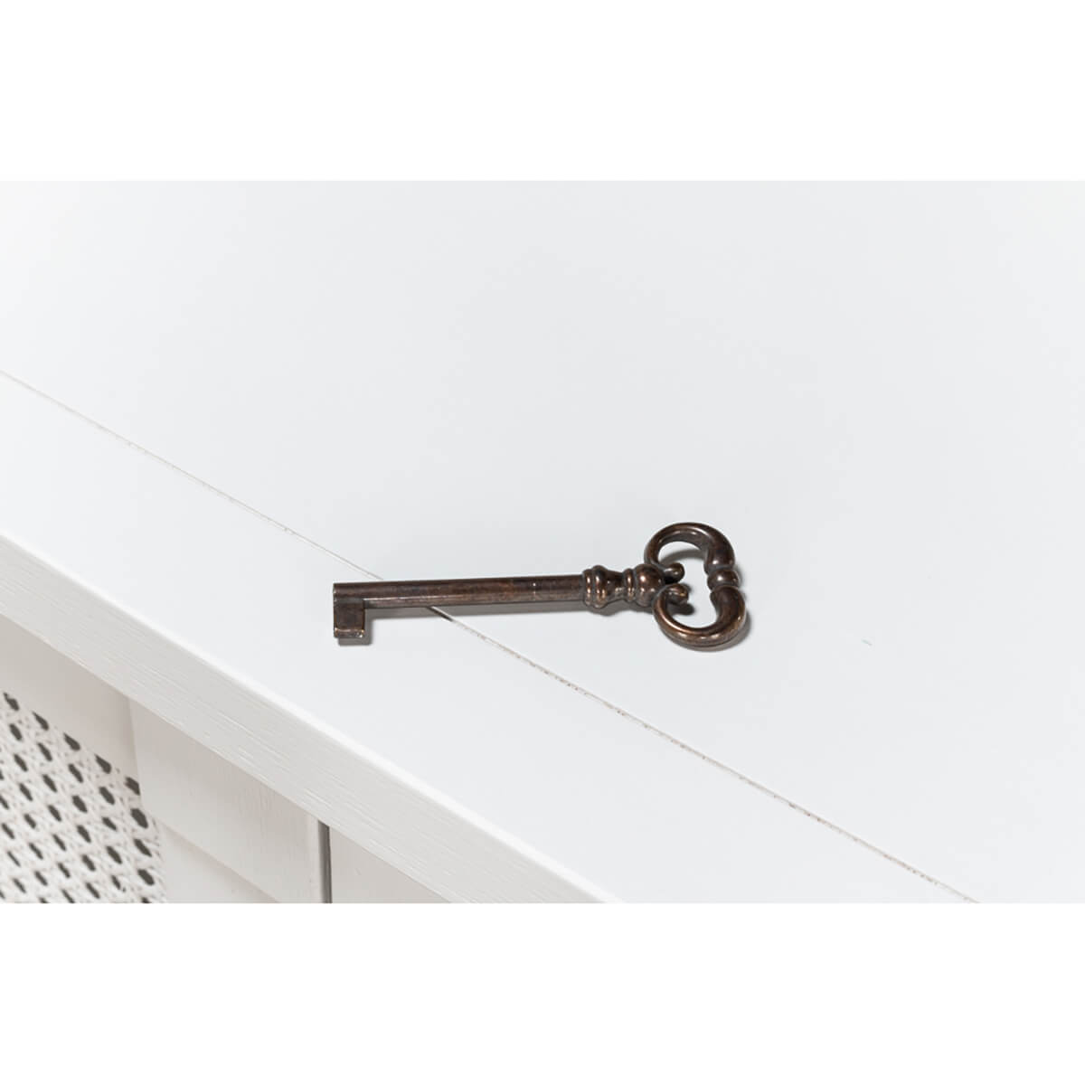 Antique key on top of white sideboard.