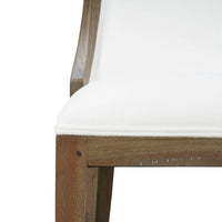 Close-up of dining chair seat edge, white upholstery.
