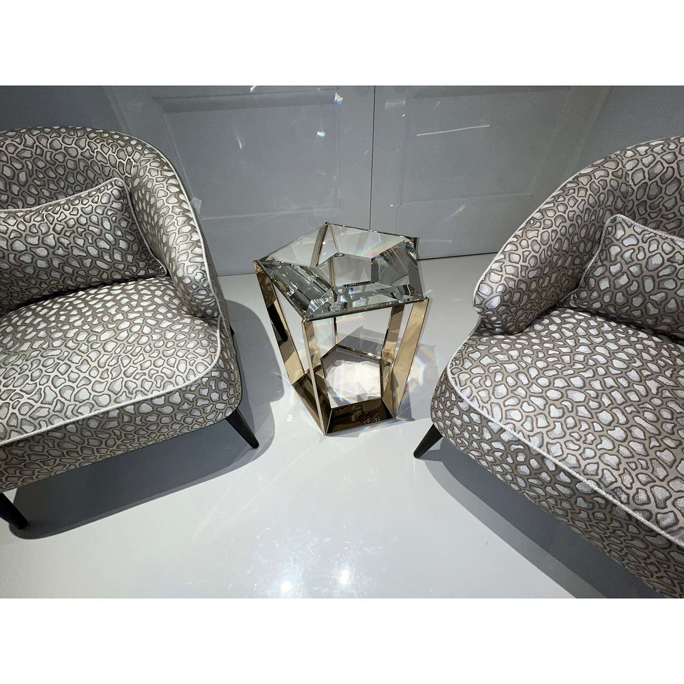 Accent table with chairs on glossy white floor.