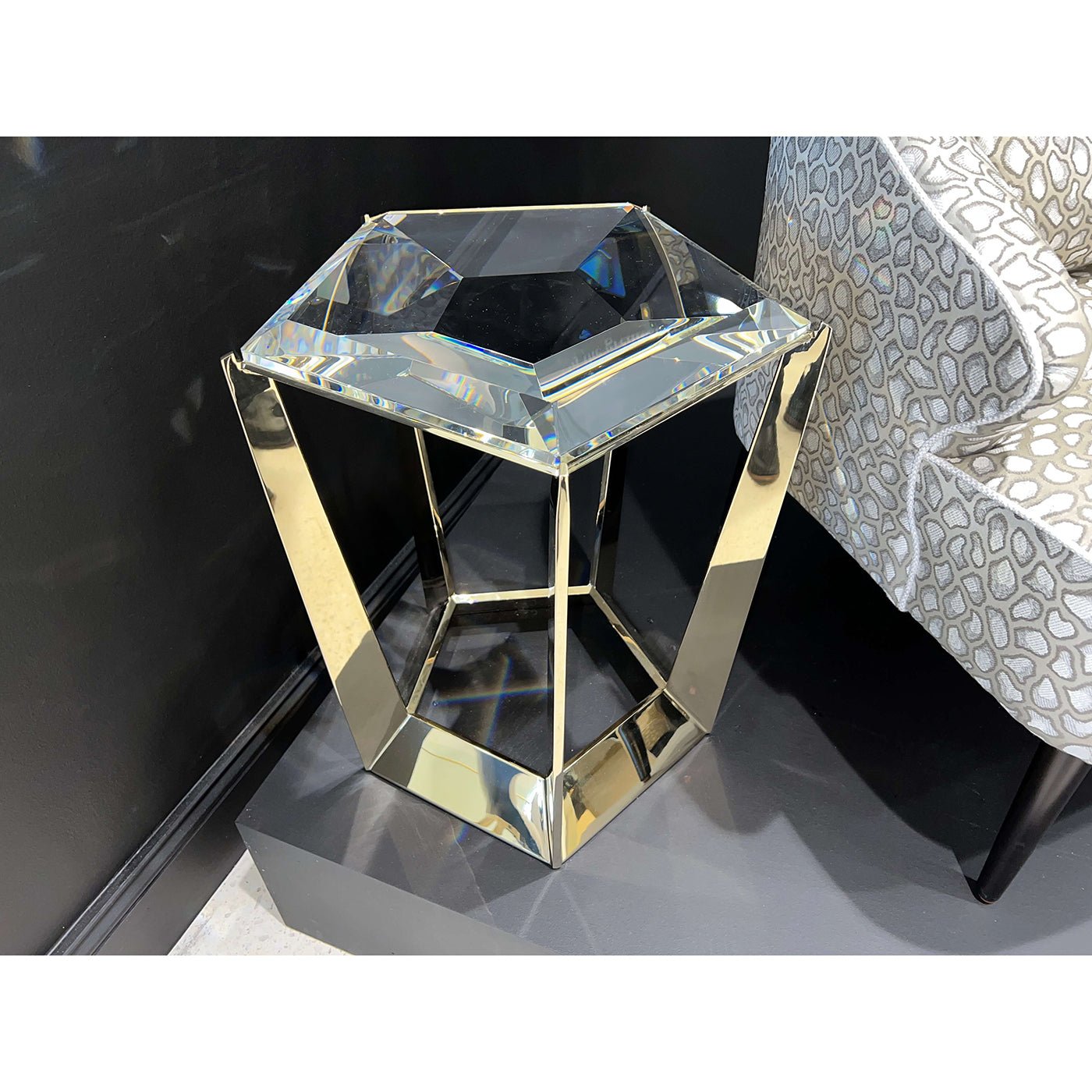 Gold frame accent table against a black wall.