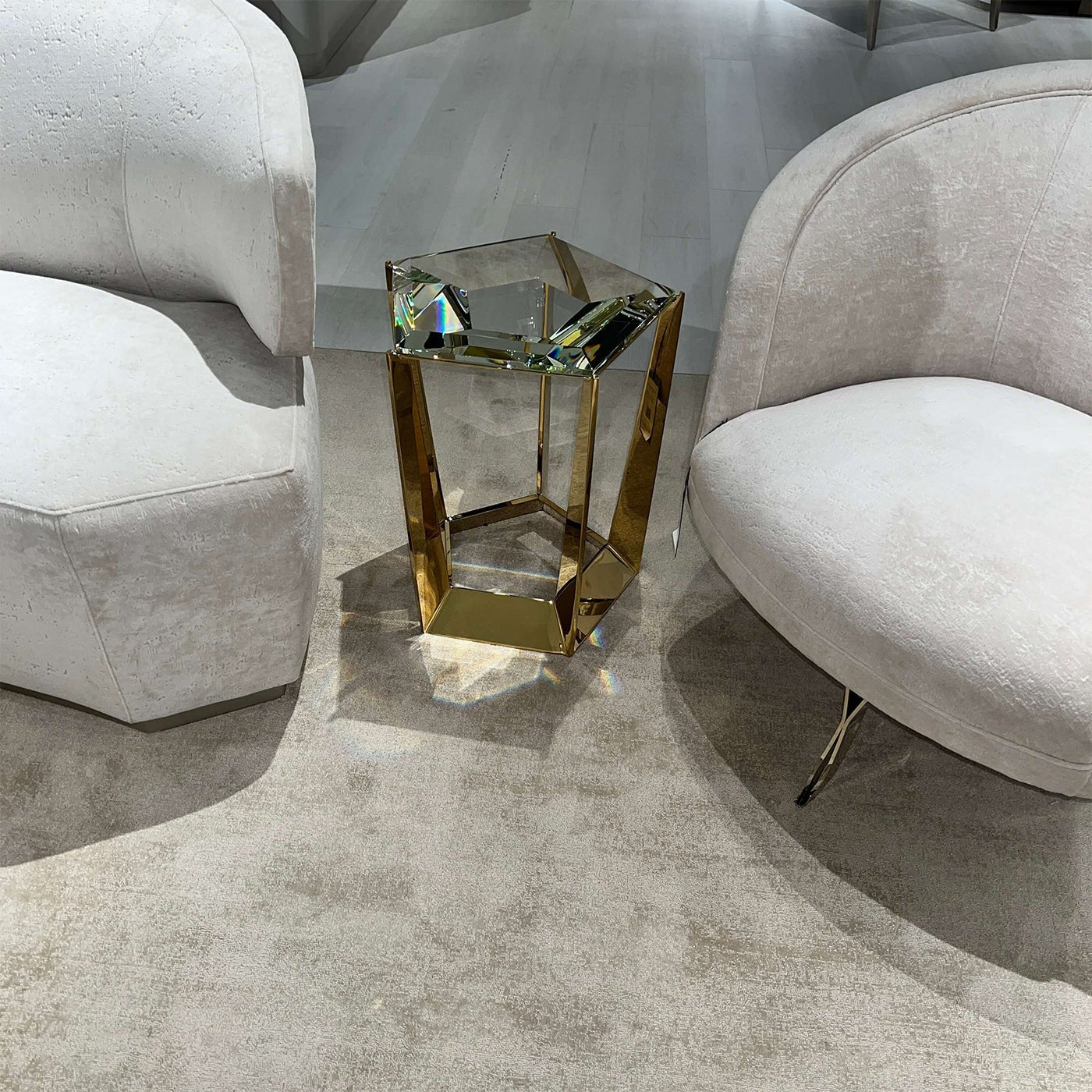 Glass accent table between two white armchairs.