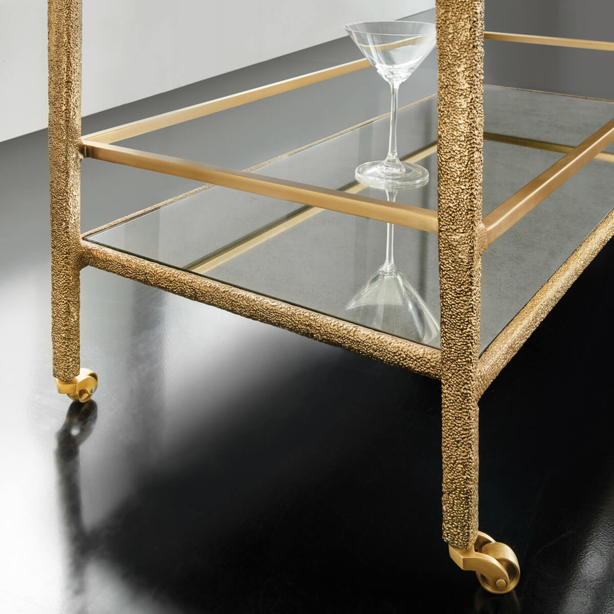 Close-up of gold bar cart wheels and lower shelf.