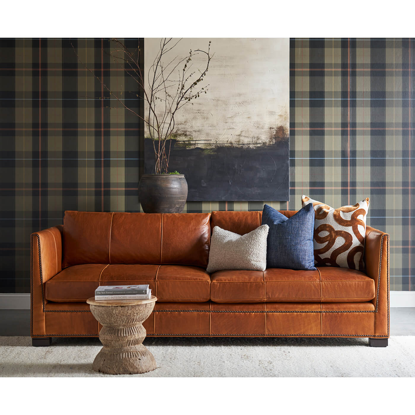 Brown leather sofa, styled living room, plaid wallpaper.