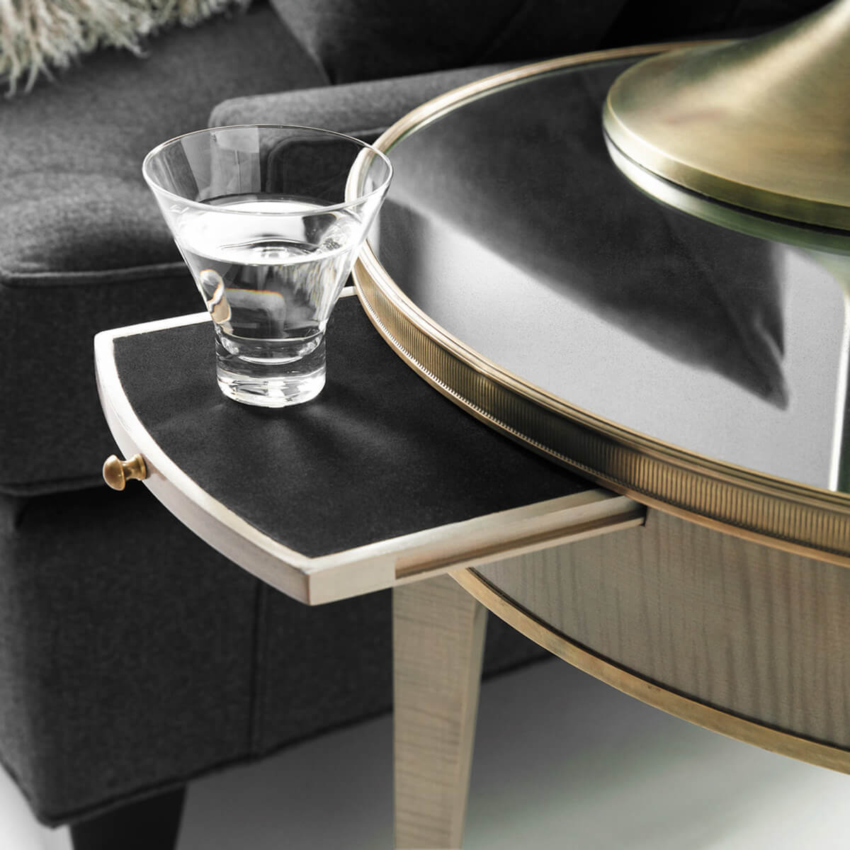 Round side table with extended drawer, close-up water glass.