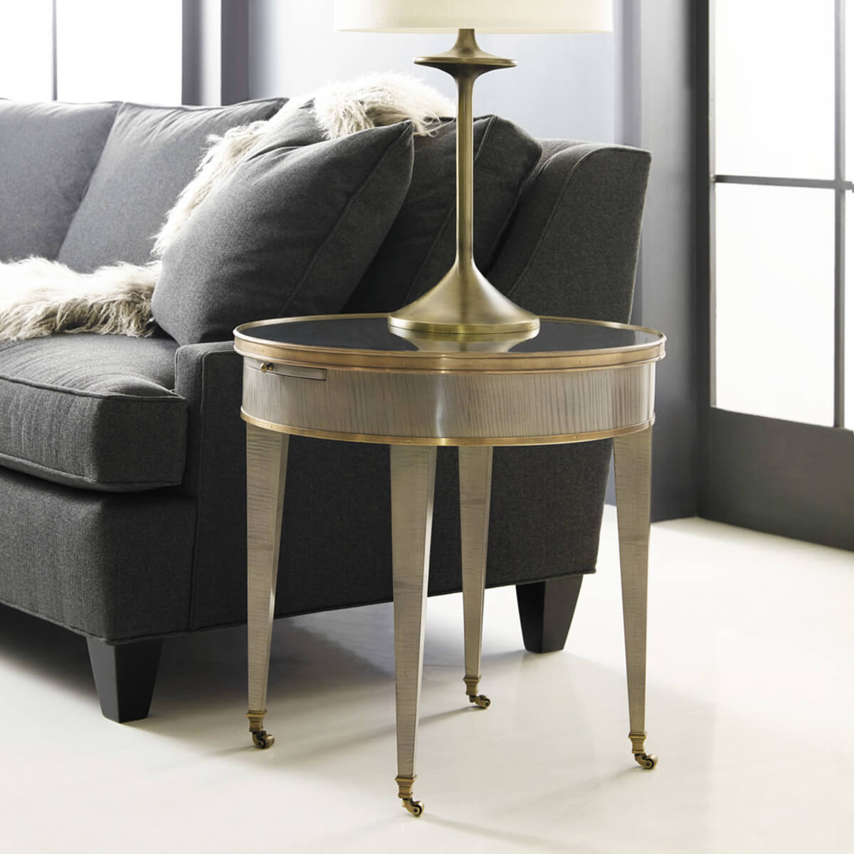 Round side table beside sofa with lamp, cozy setting.