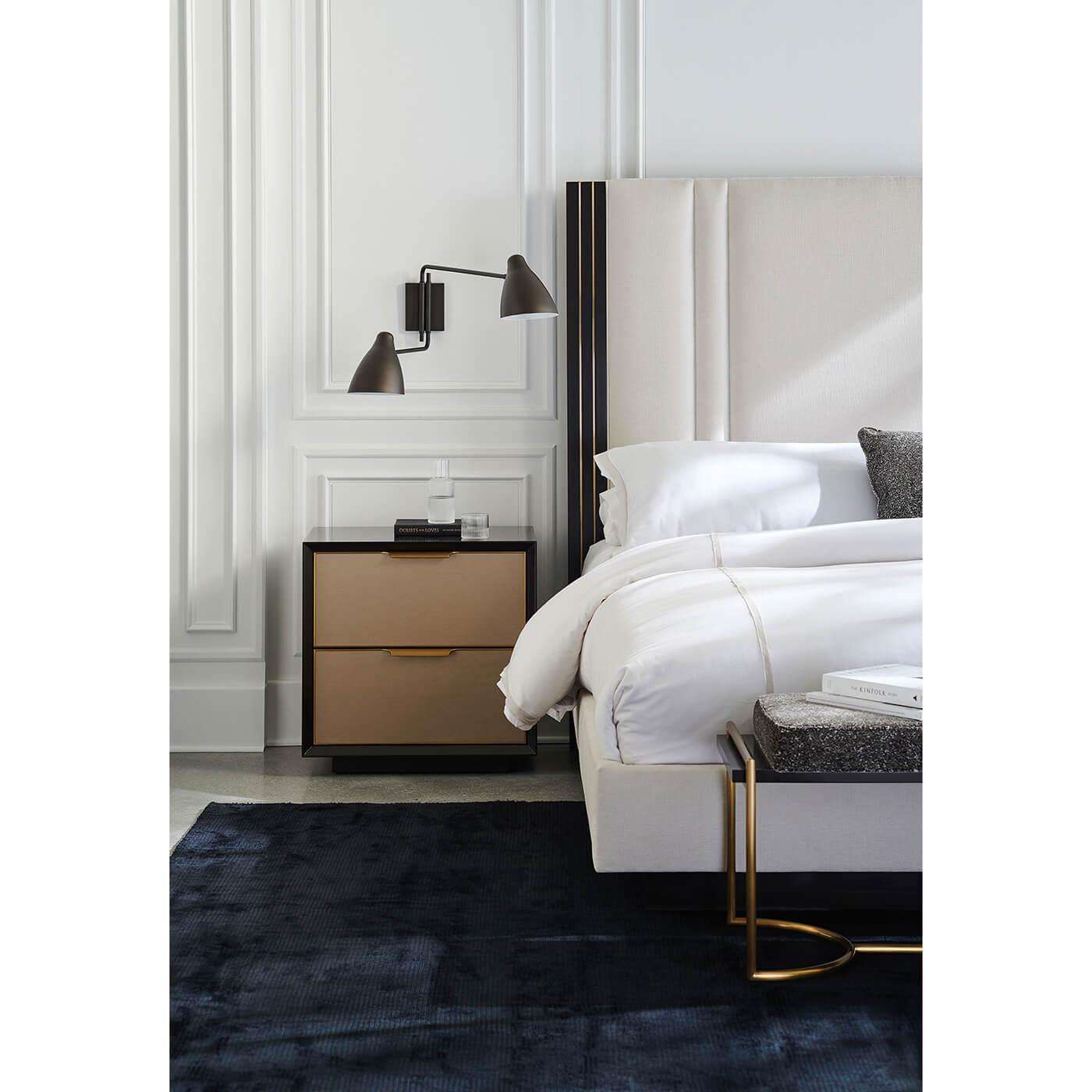 Modern king bed with nightstand, lamps, and blue rug.