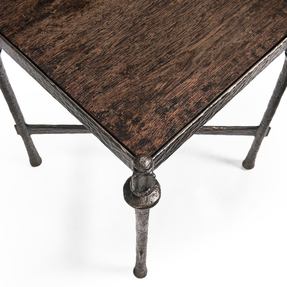 Angled top view of rustic iron side table, wood surface.