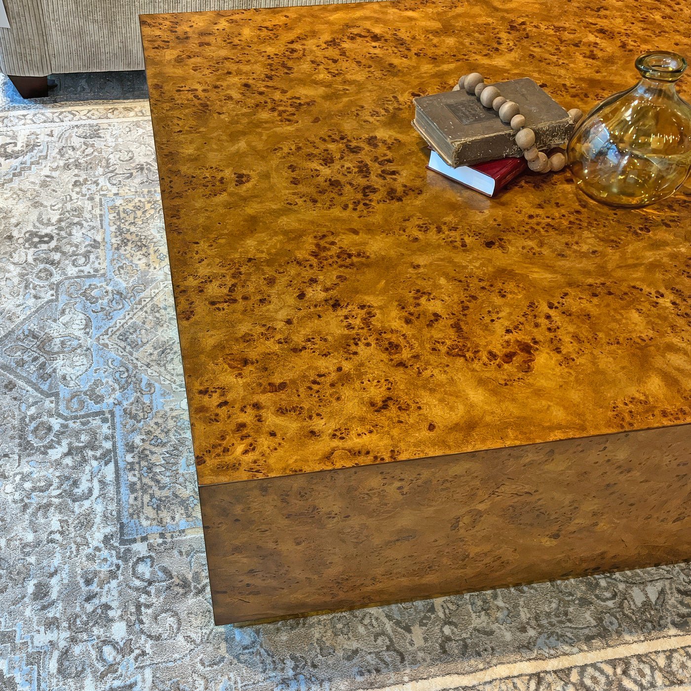 Top corner of square burl wood coffee table with decor.