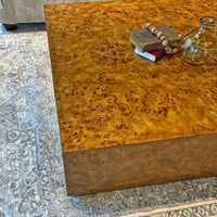 Top corner of square burl wood coffee table with decor.